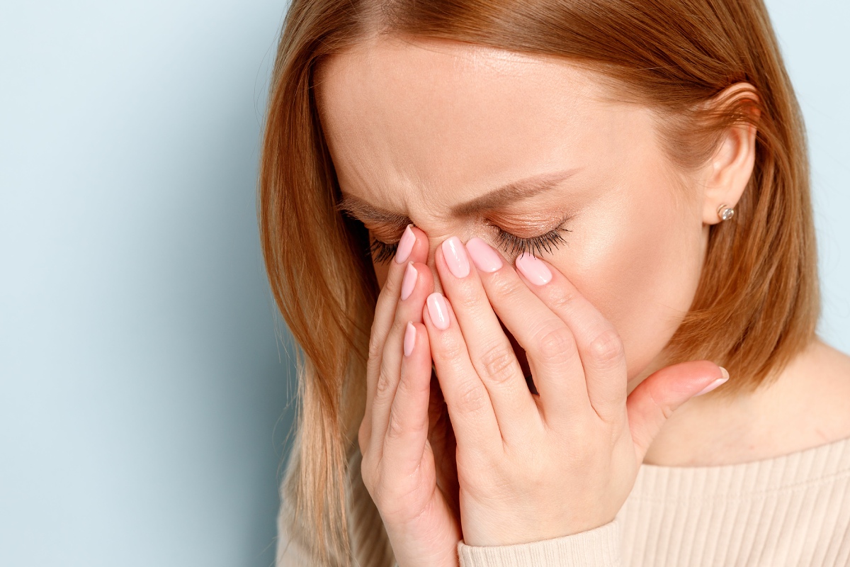 woman holding her hands to her face in discomfort