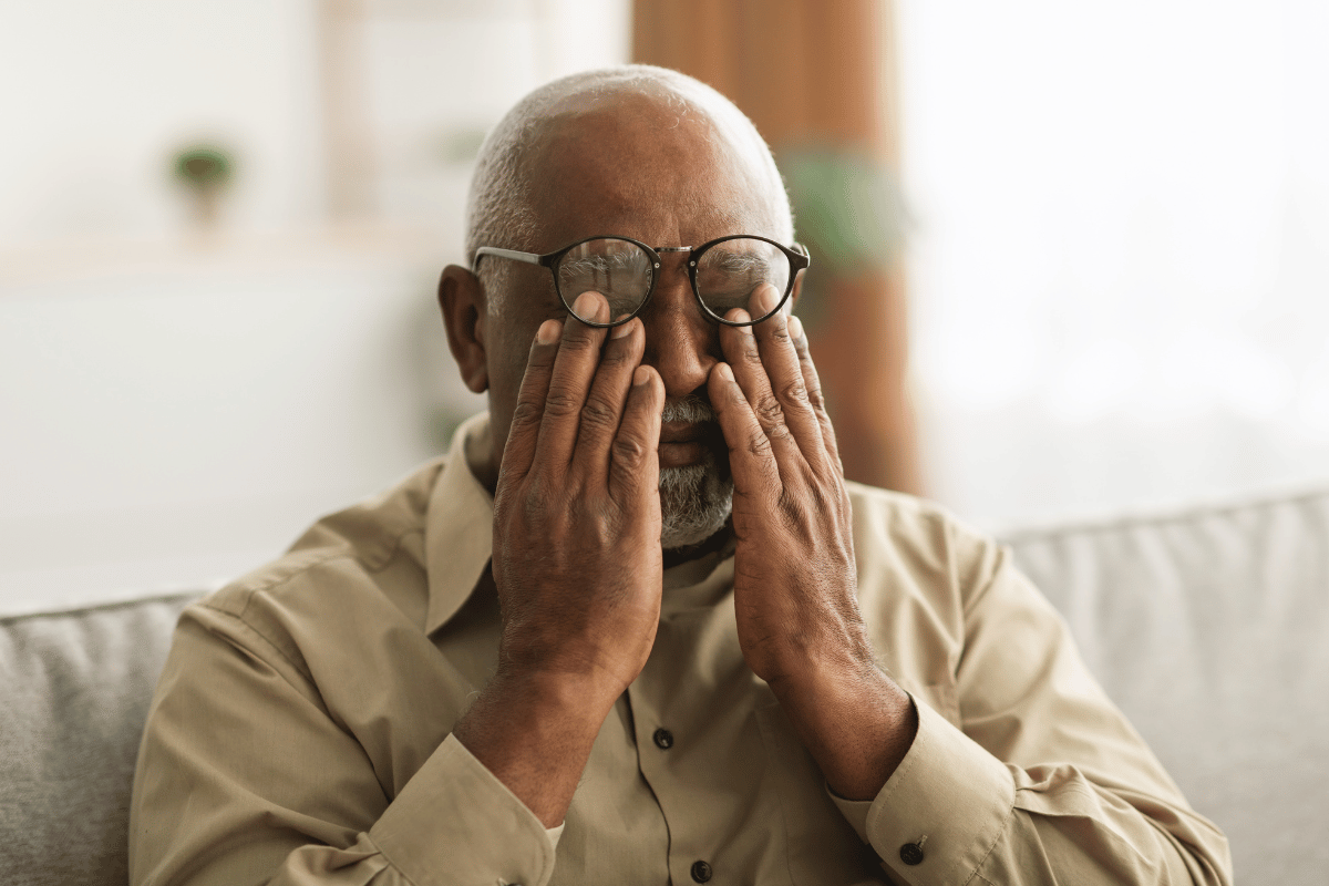 older man wearing glasses and rubbing his eyes