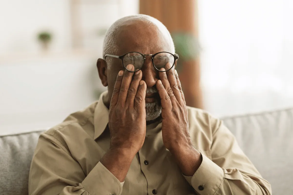 an older man wearing glasses and rubbing his eyes