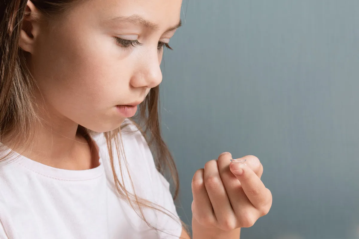 a little girl putting in a contact lens