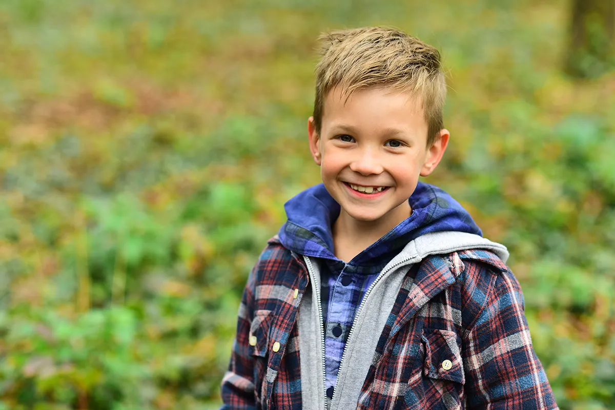 a young boy smiling while standing outside