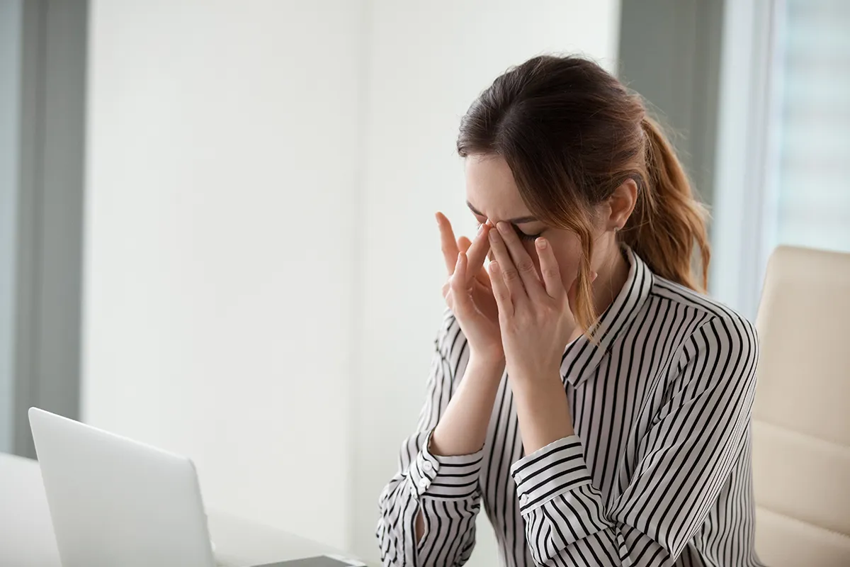a woman sitting at her computer rubbing her irritated, dry eyes